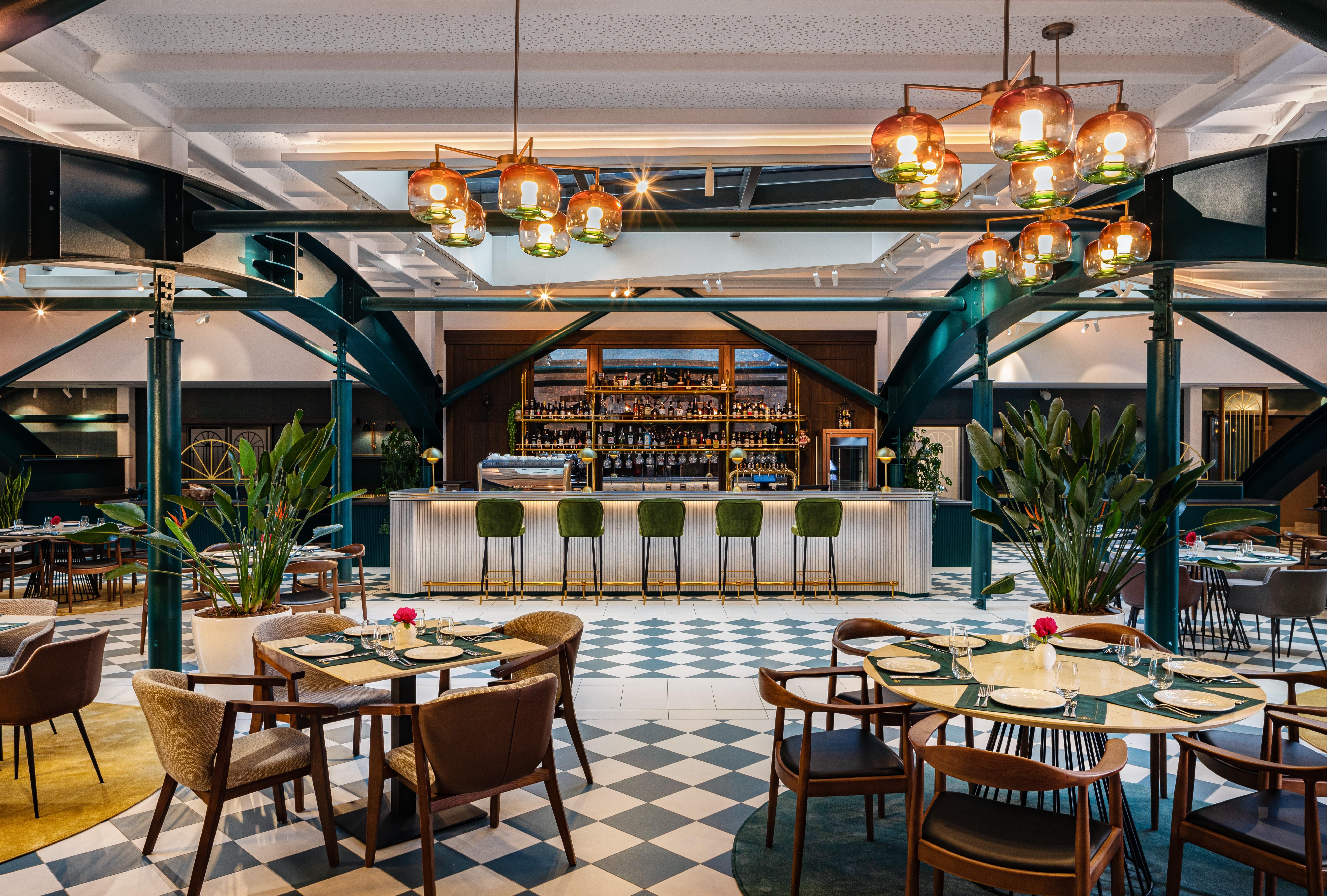 Grand Hotel Millennium 소피아 외부 사진 The photo showcases a stylish restaurant interior. There are several tables set with chairs arranged around them, featuring a mix of styles. In the background, a sleek bar counter is visible, stocked with various bottles. The bar is complemented by e