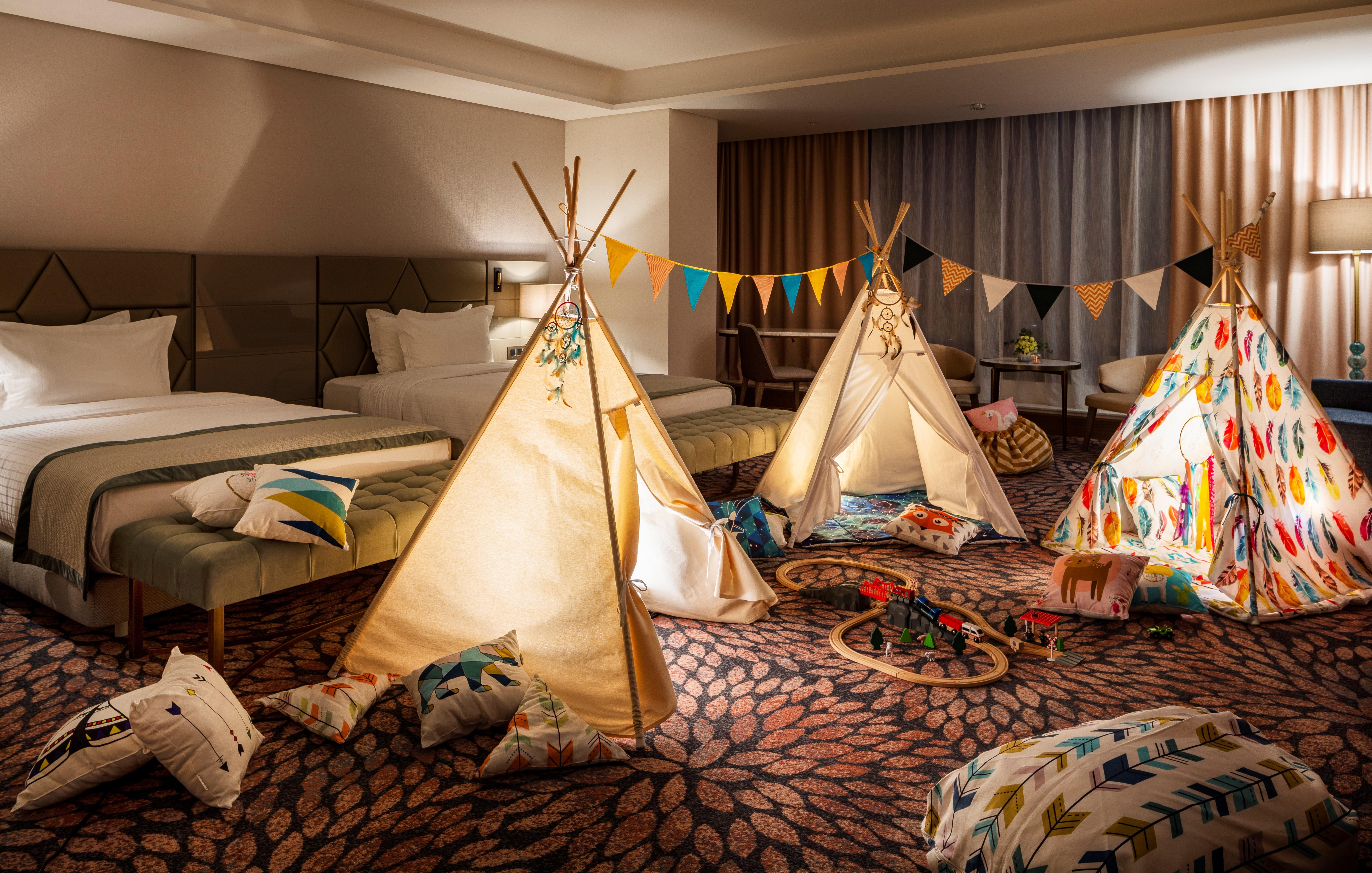 Grand Hotel Millennium 소피아 외부 사진 The photo shows a cozy room featuring three children's teepees made of fabric, arranged in a playful manner. The teepees are decorated with colorful patterns and surrounded by various cushions and pillows scattered on the floor. There are also decora