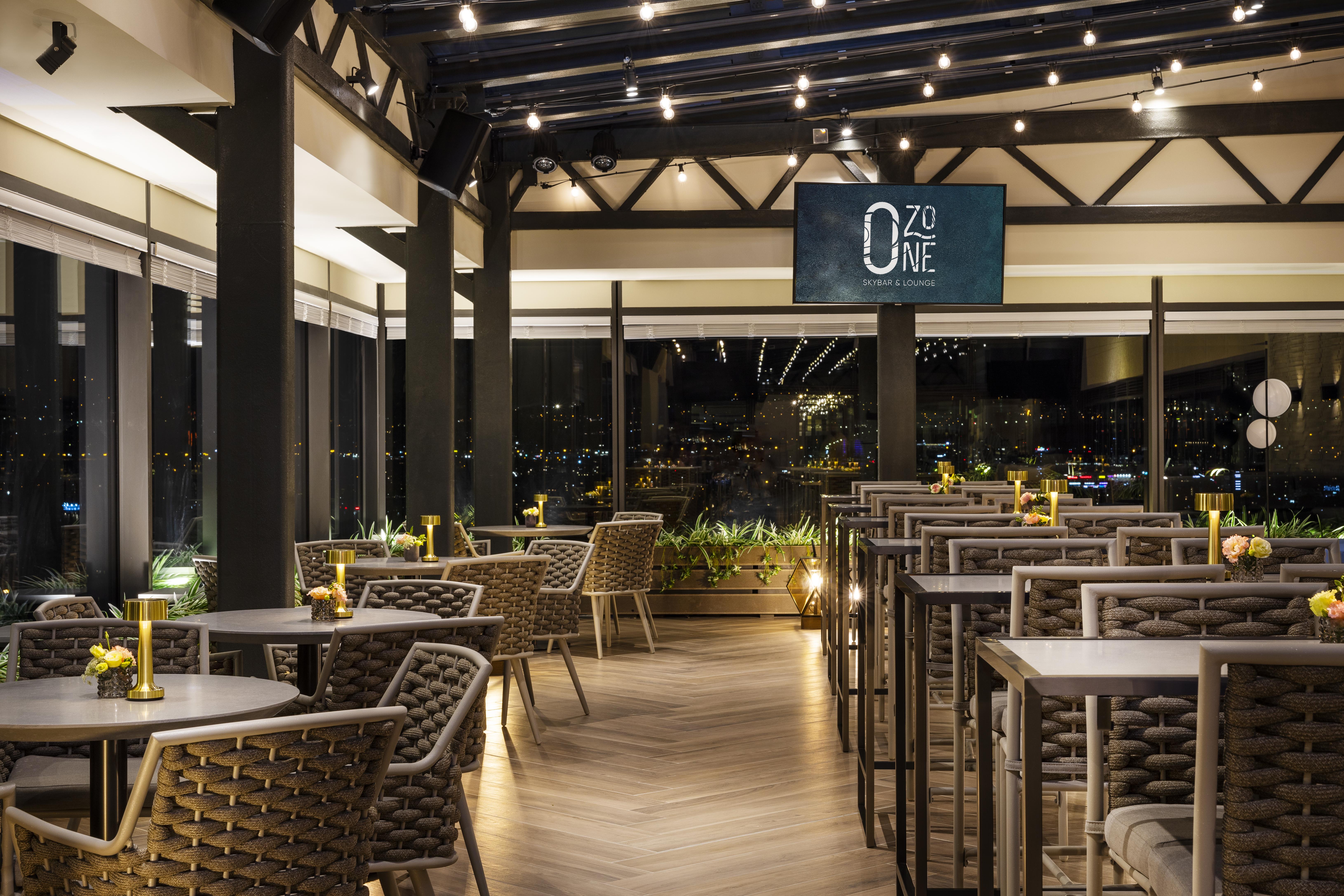 Grand Hotel Millennium 소피아 외부 사진 The photo depicts a modern restaurant interior with a stylish design. The space features a series of tables and chairs arranged neatly, with a clean and sophisticated aesthetic. The tables are set with small yellow flowers, adding a touch of color to